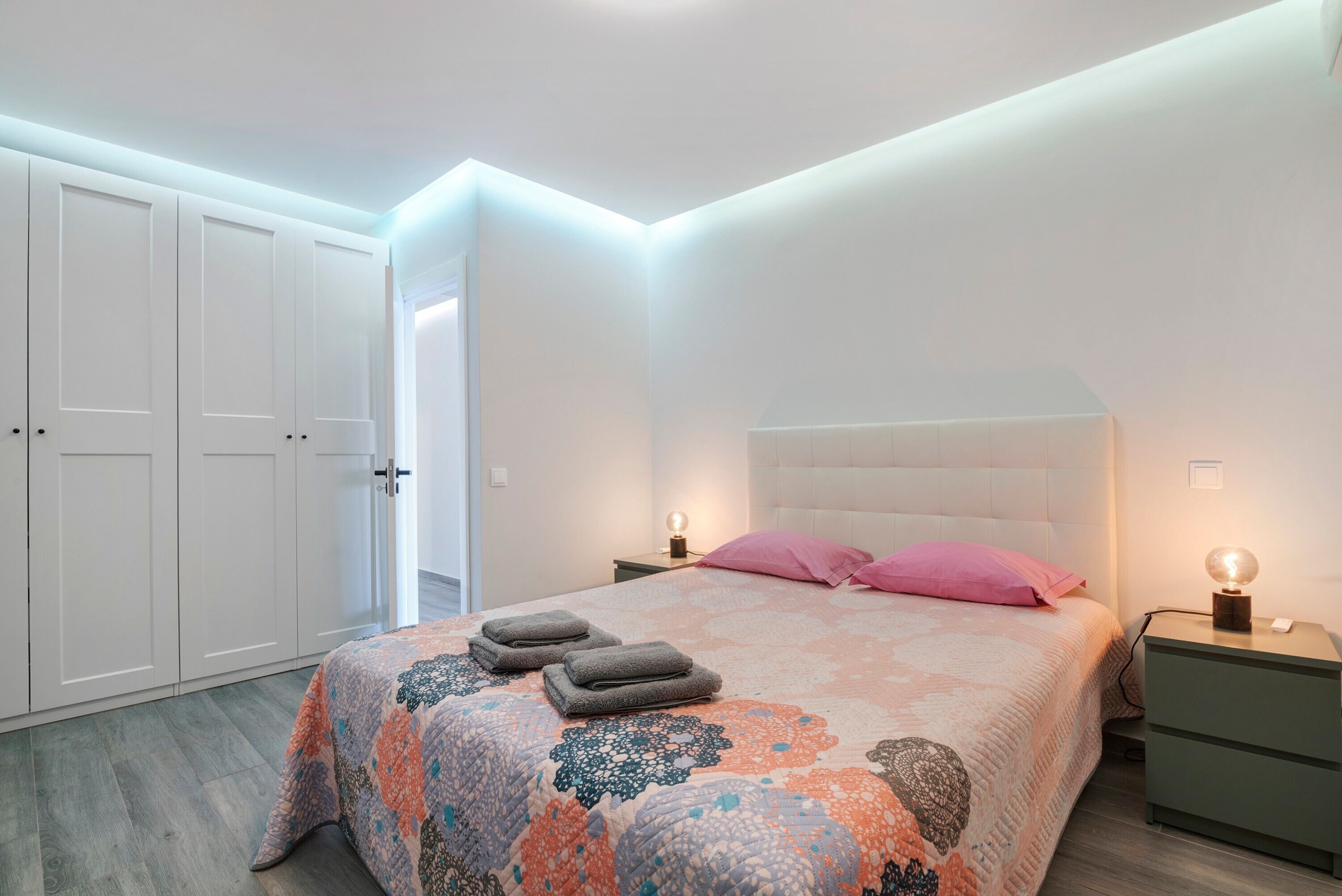 Un dormitorio con cama, dos mesitas de noche, un armario y una puerta.
