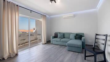 A modern living room with a sofa, a chair, and a sliding glass door leading to an outdoor area.