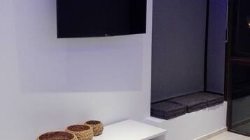 A modern living room with a flat-screen TV mounted on the wall, a white entertainment unit with baskets, and a blue accent wall.