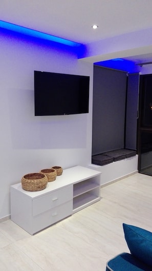 Ein modernes Wohnzimmer mit einem an der Wand befestigten Flachbildfernseher, einer weißen Unterhaltungsanlage mit Körben und einer blauen Akzentwand.