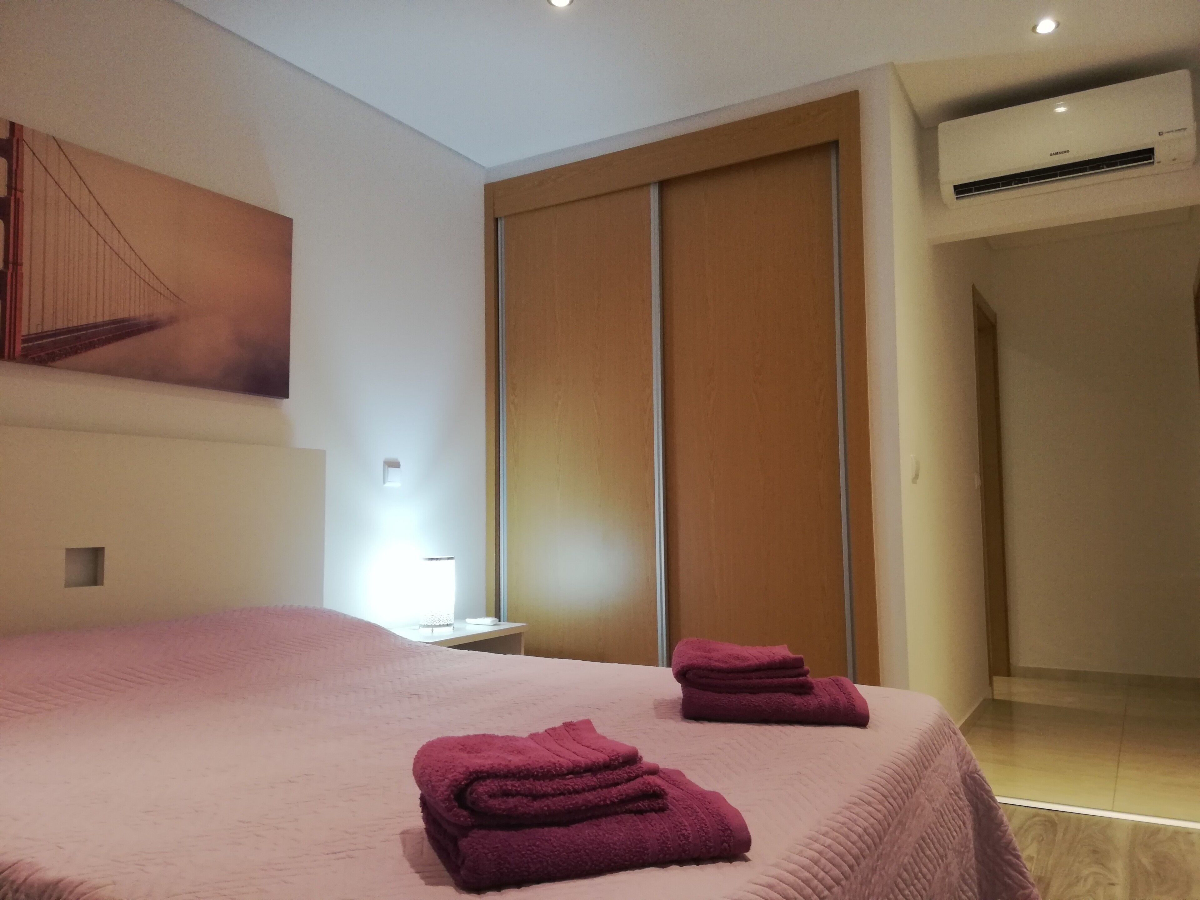 Une chambre d’hôtel moderne avec un grand lit, un climatiseur fixé au mur et un placard à portes coulissantes.