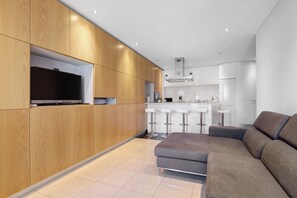 Eine moderne Küche mit Holzschnitzereien, einem eingebauten Fernseher und einem grauen Ecksofa.