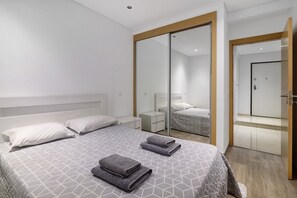 Ein modernes Hotelzimmer mit einem großen Bett, einem begehbaren Kleiderschrank und einem separaten Badezimmer.