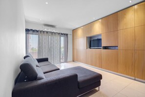 Ein modernes Wohnzimmer mit einer Couch, Holzschränken und einem Flachbildfernseher.