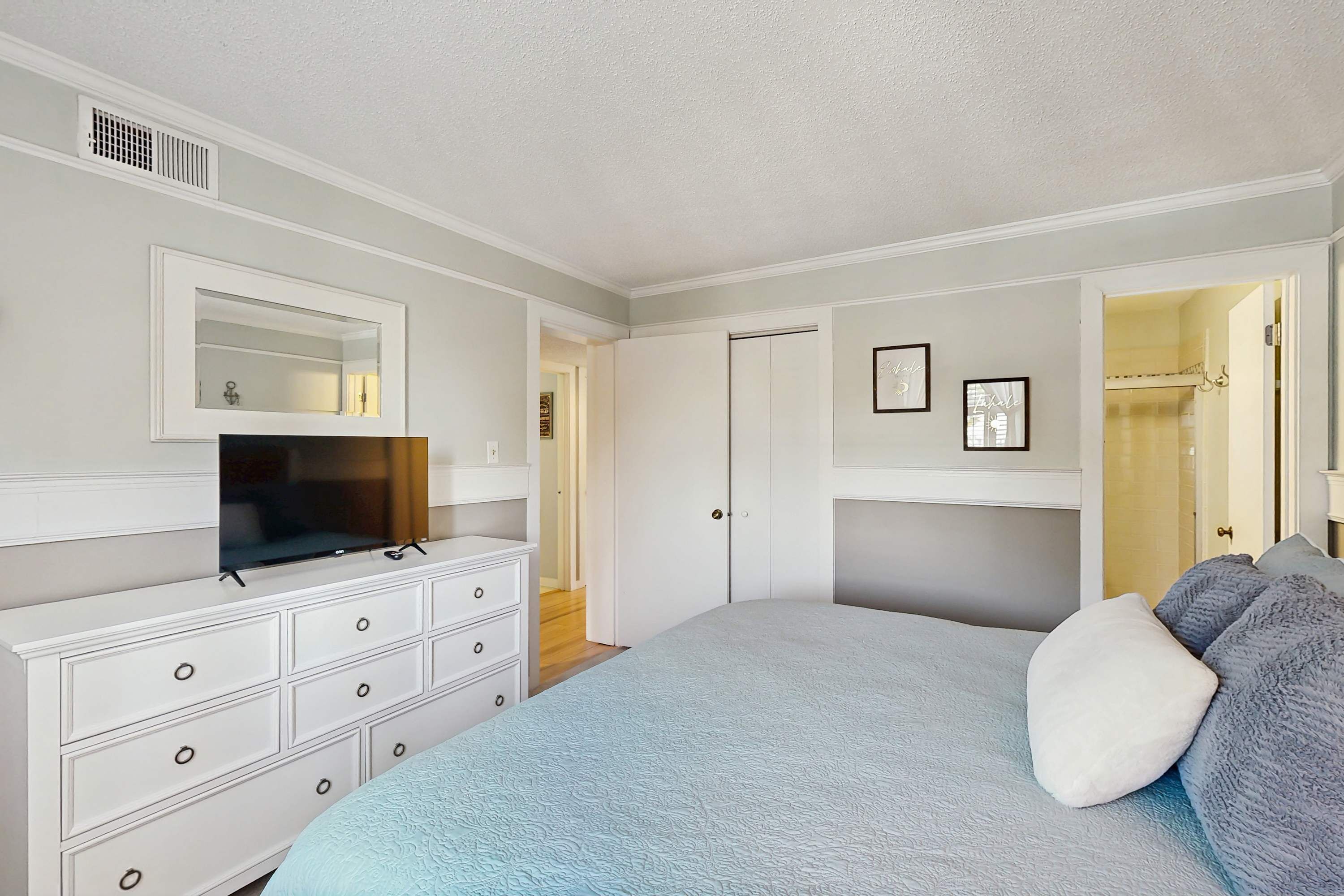 A bedroom with a bed, dresser, TV, and a closet.