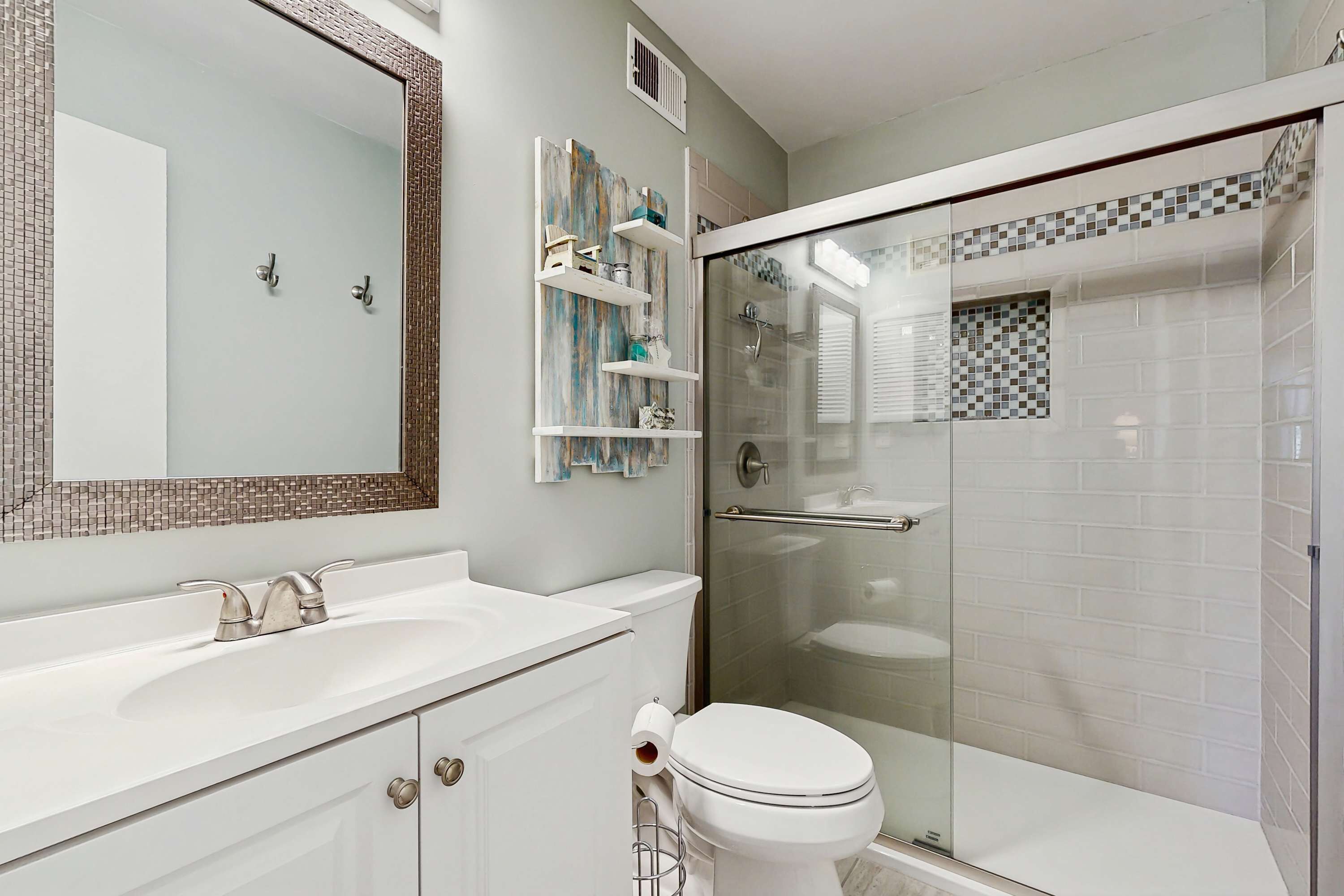 A bathroom with a glass-enclosed shower, a white sink, and a toilet.