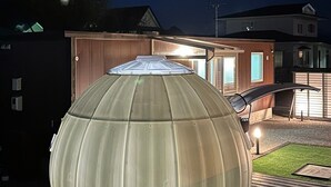 Uma estrutura grande, transparente e em forma de cúpula em um quintal à noite.