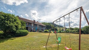 A grassy yard with a swing set and a house in the background.