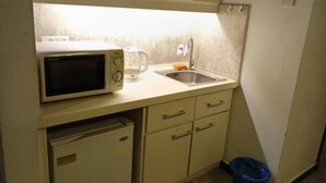 A compact kitchenette with a microwave, coffee maker, sink, and a small refrigerator. - Berjaya Times Square Apartment (Kuala Lumpur)