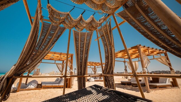A beachside lounge with woven canopies, wooden loungers, and a clear view of the ocean. - Makai Hotel North Coast By Brassbell (El Dabaa)
