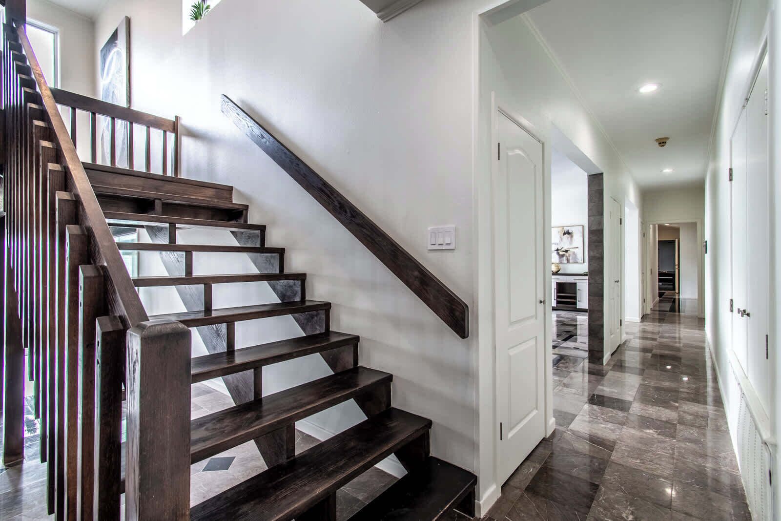 A staircase with dark wooden steps and a handrail, leading to a white door.