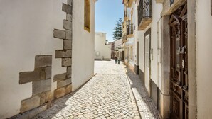A narrow cobblestone street flanked by buildings with white walls and wooden doors. - Private Rooftop w/ Pool in Tavira (Tavira)