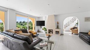 Ein großzügiges Wohnzimmer mit einer Ledersofa, einem Glastisch und einem Kamin.