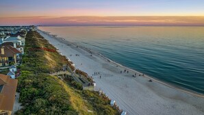 Une plage avec une promenade en bois et des maisons le long du rivage.
