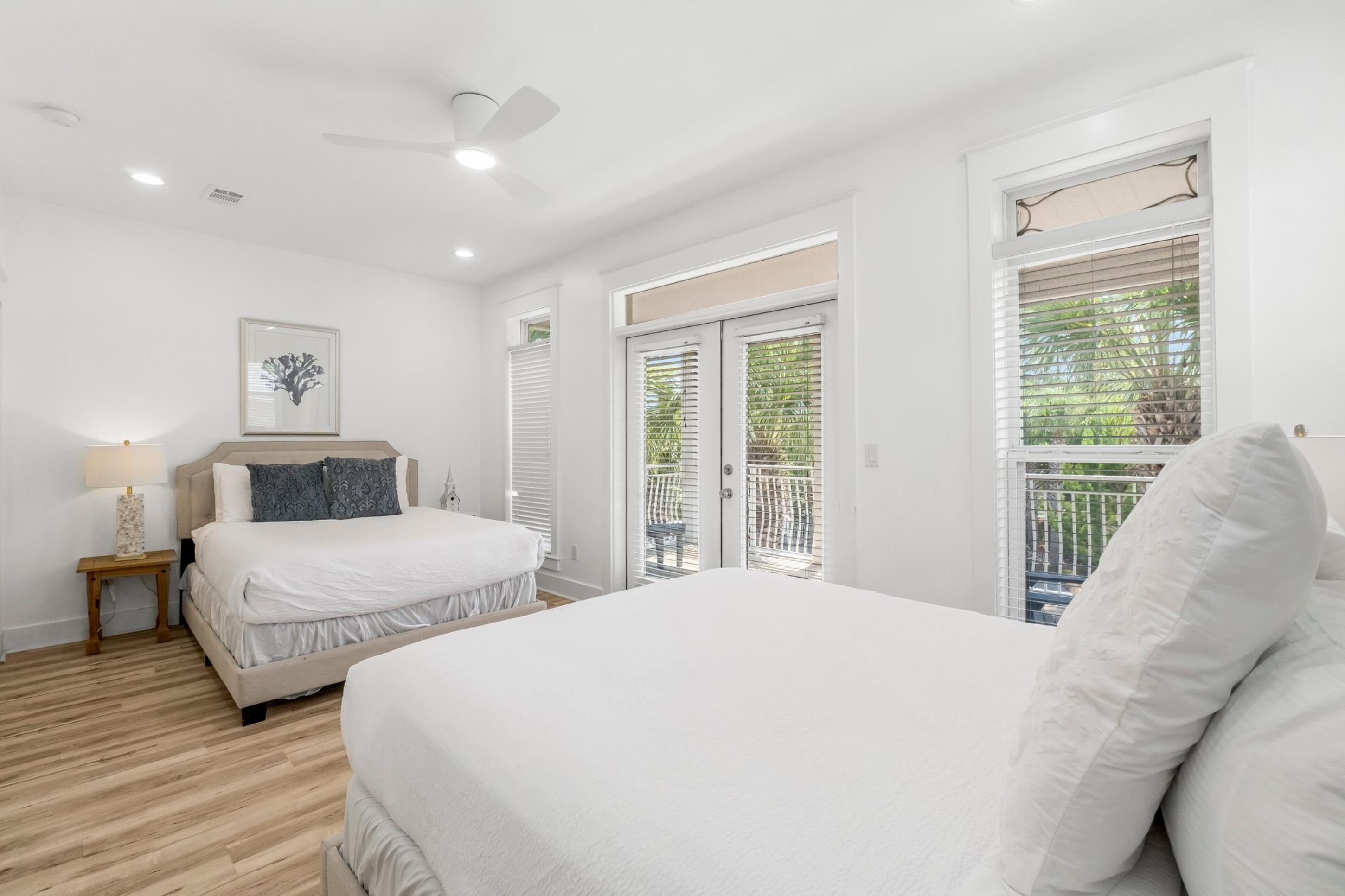 A bedroom with a bed, a nightstand, a ceiling fan, and a window with blinds.