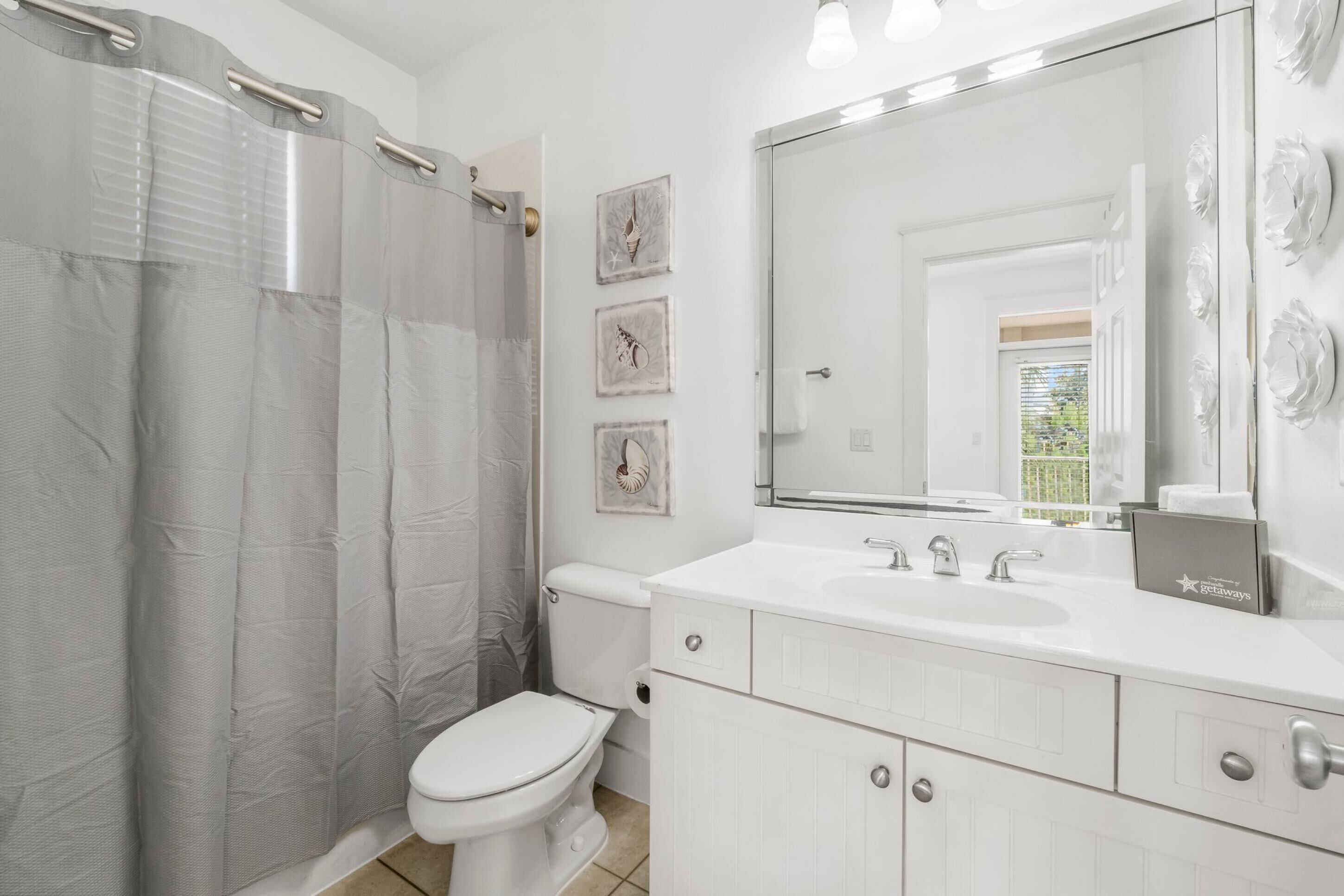 A bathroom with a toilet, a sink, a mirror, and a shower curtain.