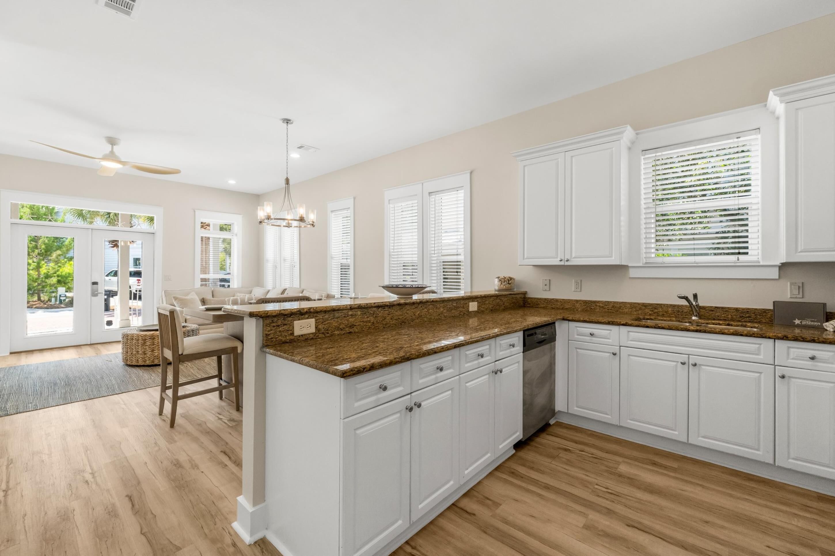 A modern kitchen with white cabinets, granite countertops, and a dining area with a chair and table.
