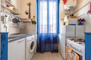 A compact kitchen with a washing machine, a stove, and a refrigerator. - Blue River Trastevere (Rome)