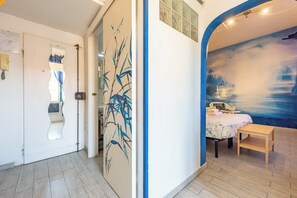 Ein Zimmer mit einem Bett, einem kleinen Tisch und einer Wand mit einem Gemälde.