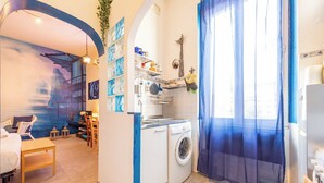 A compact living space with a washing machine, a dining area with a table and chairs, and a mural on the wall. - Blue River Trastevere (Rome)