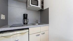 Cozinha compacta com micro-ondas, cafeteira e máquina de lavar louça.