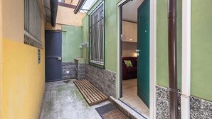 A narrow hallway with a door leading to a room, a small table, and a bench. - Hostdomus - Lizzie's House (Alassio)