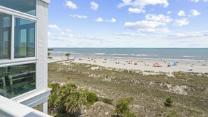 Vista de una playa desde un edificio con amplios ventanales, playa de arena y océano.