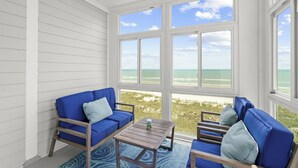 Una habitación con vista a la playa, un sofá azul, una mesa de madera y una alfombra estampada.