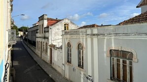 A narrow street with historic buildings, one with a white facade and arched windows, another with a red-tiled roof, and a third with a balcony. - Cozy Figueira Apartment (Figueira da Foz)