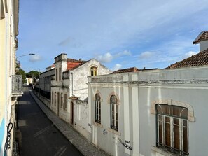 A narrow street with historic buildings, one with a white facade and arched windows, another with a red-tiled roof, and a third with a balcony. - Cozy Figueira Apartment (Figueira da Foz)