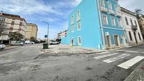 A street view with a blue building, a crosswalk, and a roundabout. - Cozy Figueira Apartment (Figueira da Foz)