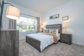 A bedroom with a bed, bedside lamps, a nightstand, a window with curtains, and a wall with two framed pictures. - 4BR Home at Storey Lake w/ Private Pool (Kissimmee)