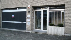 A building with a garage door, a glass entrance, and a brick facade.