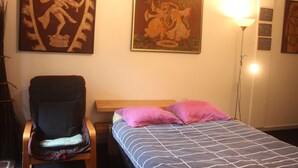 A room with a bed, a chair, and two wall-mounted paintings.