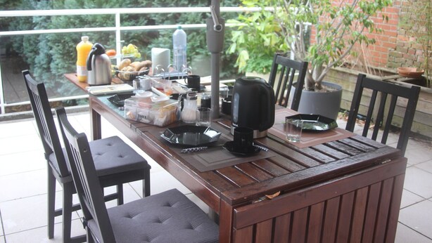 A wooden dining table with chairs, a coffee maker, and various breakfast items.