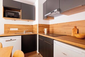 A modern kitchen with black cabinets, a Bosch dishwasher, and wooden countertops.