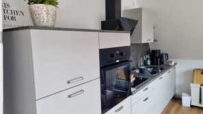 A modern kitchen with white cabinetry, a built-in oven, and a stainless steel sink. - 4 room apartment close to the beach Apartment with large 30m² balcony (Büsum)