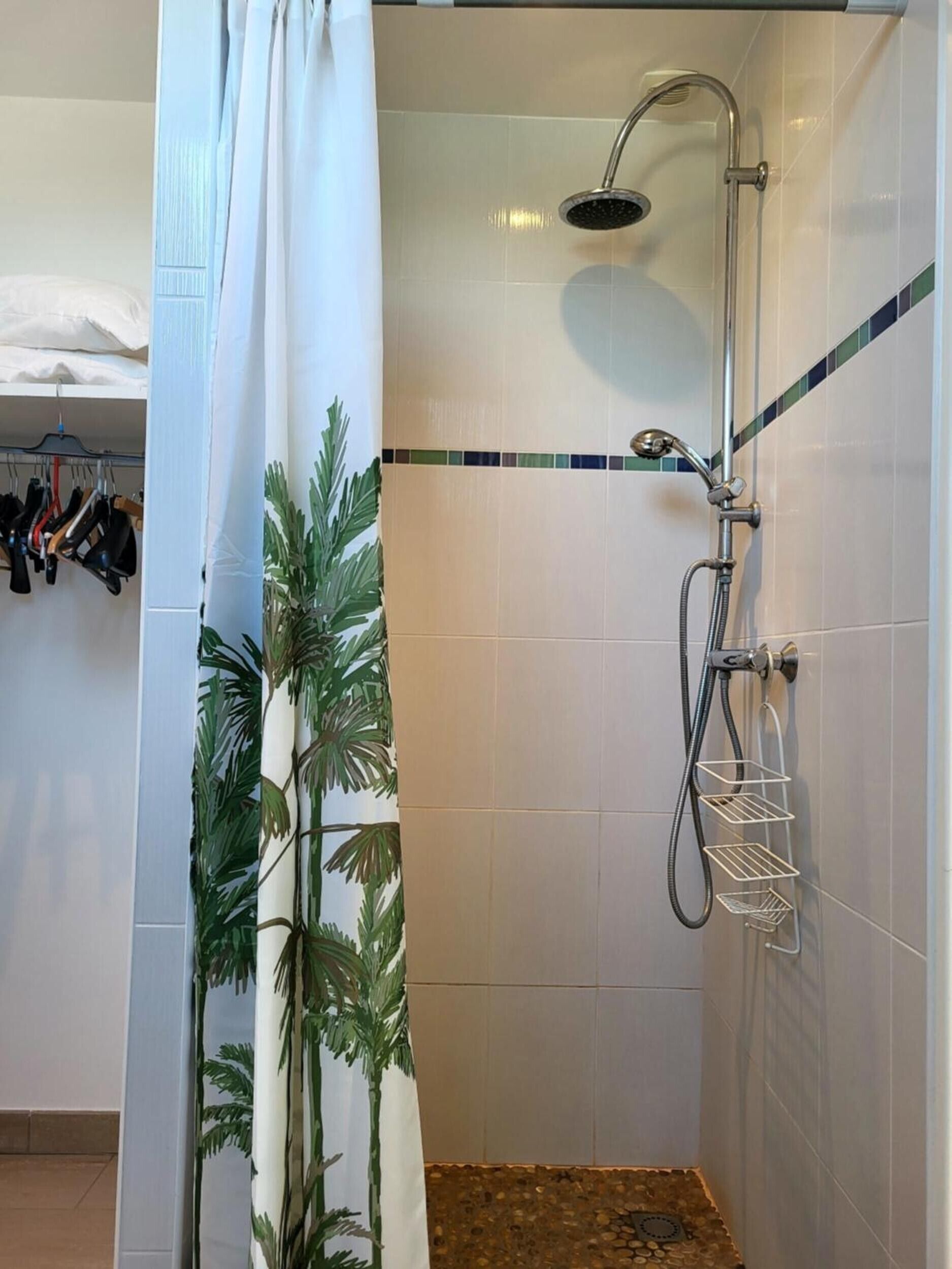Eine Dusche mit Handbrause, Wandarmatur und Duschkorb.