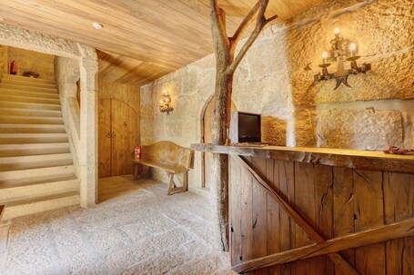A stone staircase leading to a wooden door, a stone wall with a wooden bench, and a rustic wooden counter with a stone backdrop.. Prince Room in Portugraal Castle