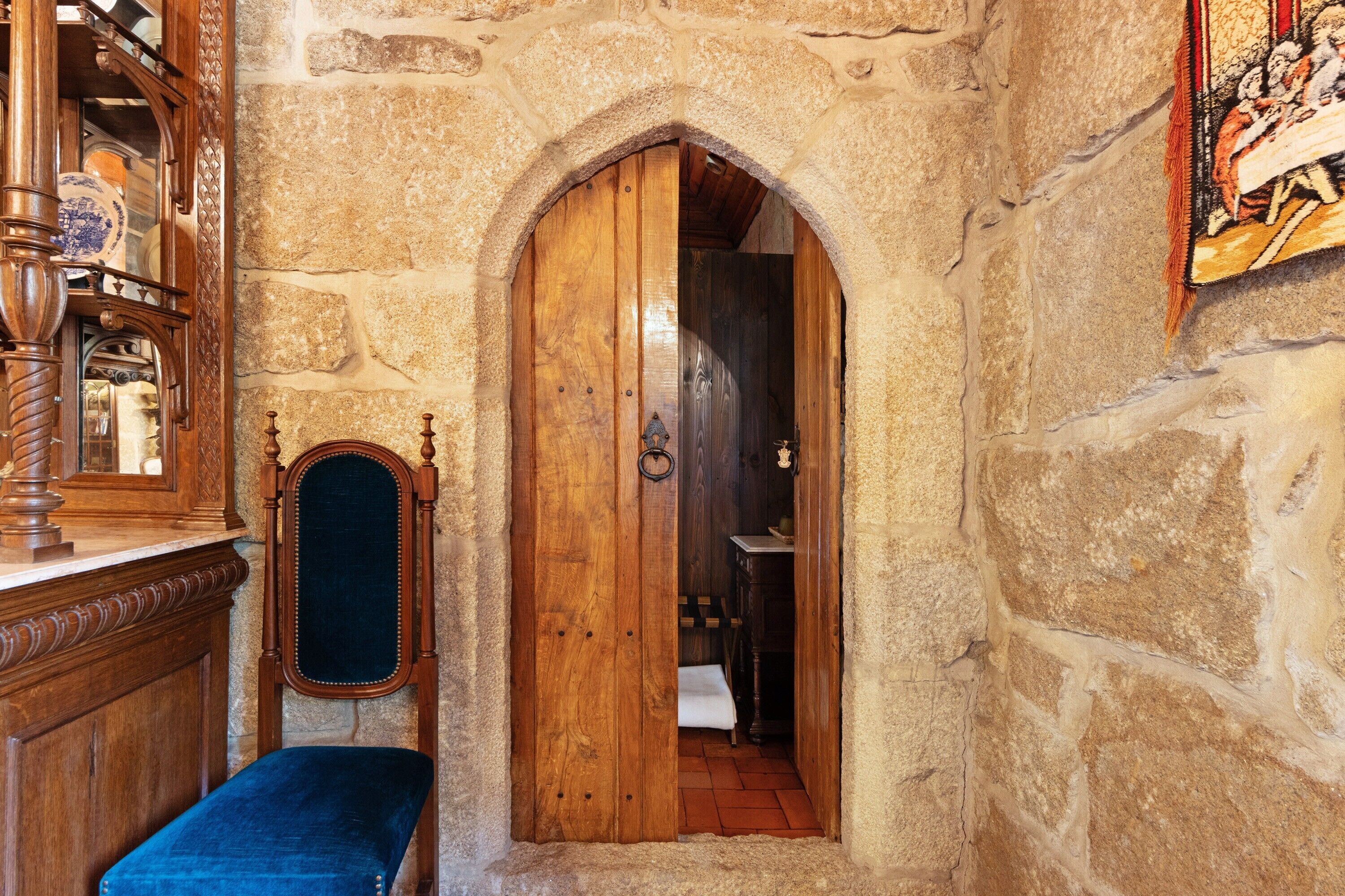 A stone-walled room with a wooden door, a bench, and a mirror.