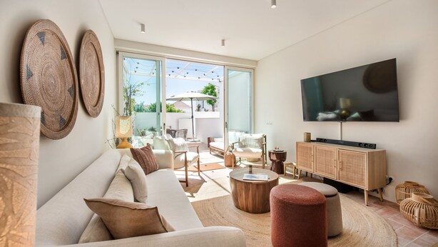 A modern living room with a sofa, coffee table, TV, and a view of the outdoors. - Casa da Saudade in Tavira (Tavira)