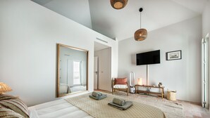 A modern hotel room with a large bed, a television, a chair, and a small table with a lamp. - Casa da Saudade in Tavira (Tavira)