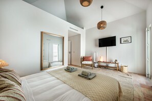 A modern hotel room with a large bed, a television, a chair, and a small table with a lamp. - Casa da Saudade in Tavira (Tavira)