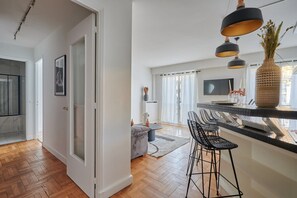 Eine moderne Küche mit Barbereich, Holzboden und Pendelleuchten.