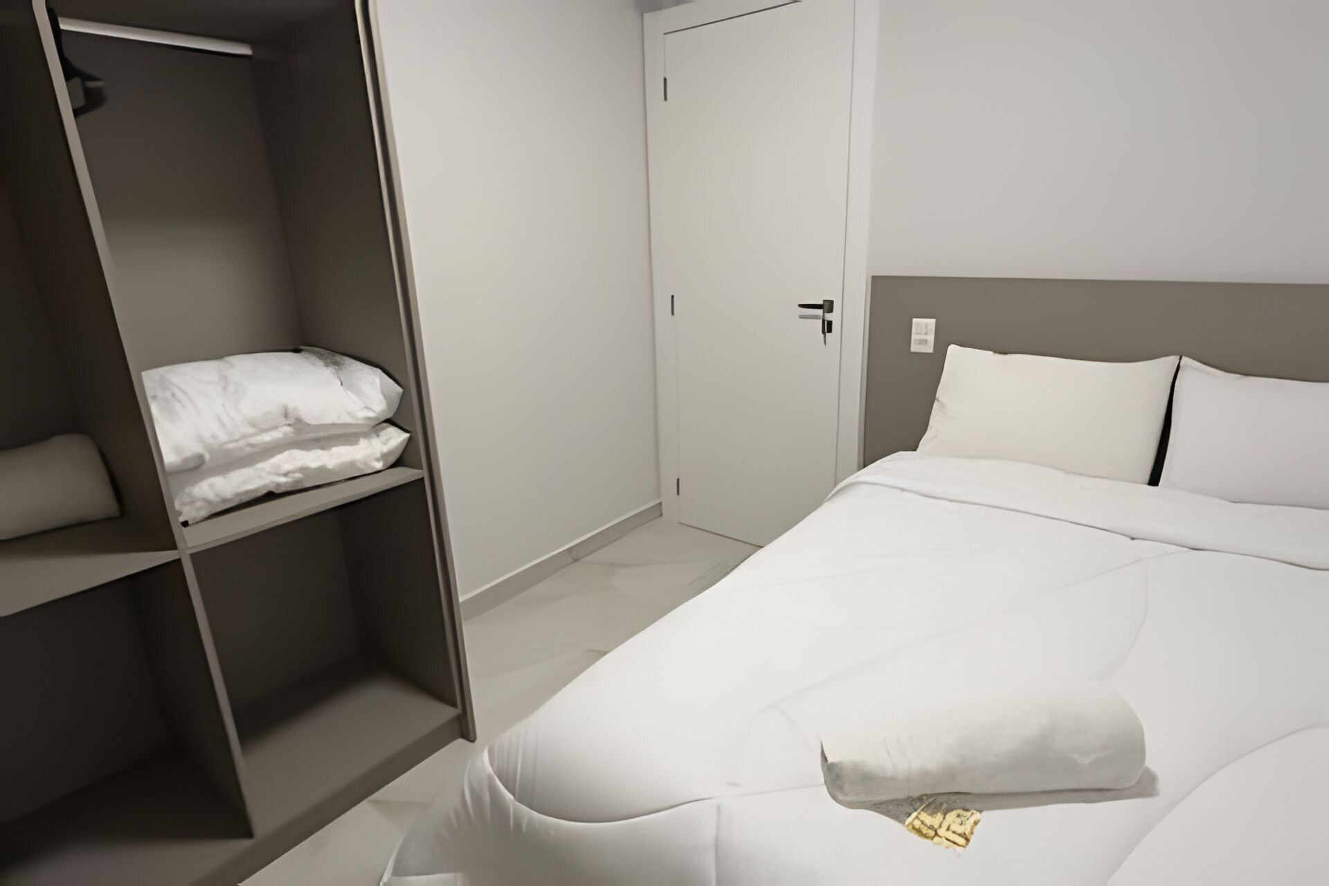 A hotel room with a bed, a wardrobe, and a door.