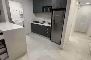 A modern kitchen with grey cabinets, a stainless steel refrigerator, and a white countertop. - Apartamento no centro de Foz do Iguaçu (Foz do Iguaçu)