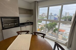 Una habitación con una mesa de comedor, sillas, zona de cocina y un amplio ventanal con vistas a la ciudad.
