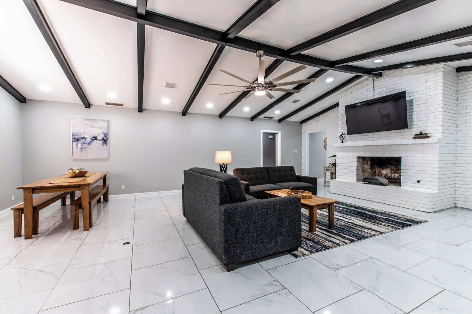 Ein modernes Wohnzimmer mit Kamin, einer Couch, einem Couchtisch und einem Essbereich mit einer Bank und Tisch.