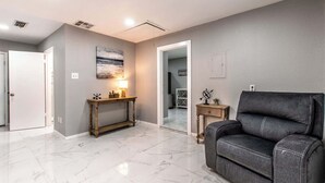 Ein modernes Wohnzimmer mit einer grauen Couch, einem Holztische und einem Marmorboden.