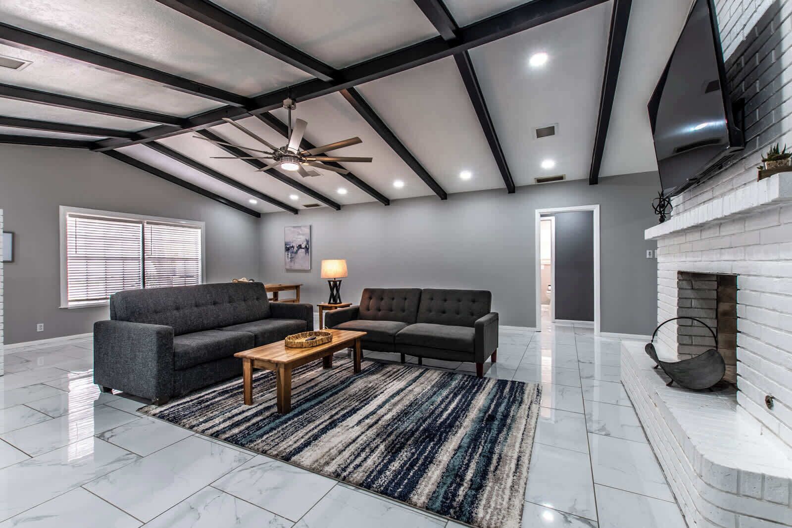 A spacious living room with a high ceiling, a fireplace, and a large window.